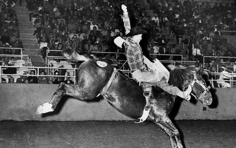 Man jumping horse in front of an audience  